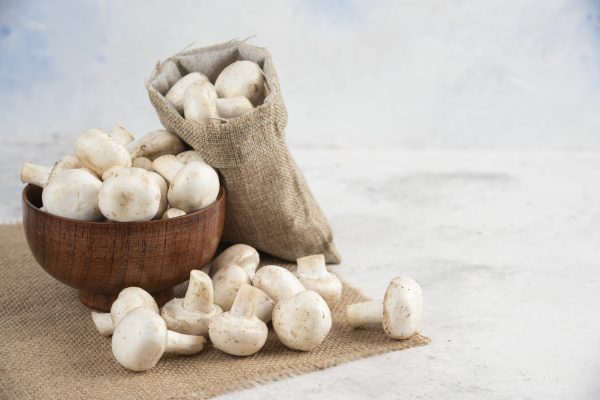 White mushrooms in a wooden cup on a piece of burlap. High quality photo